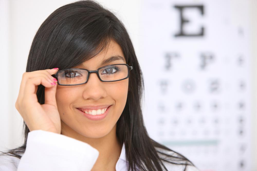 woman wearing glasses in front of an eye exam chart